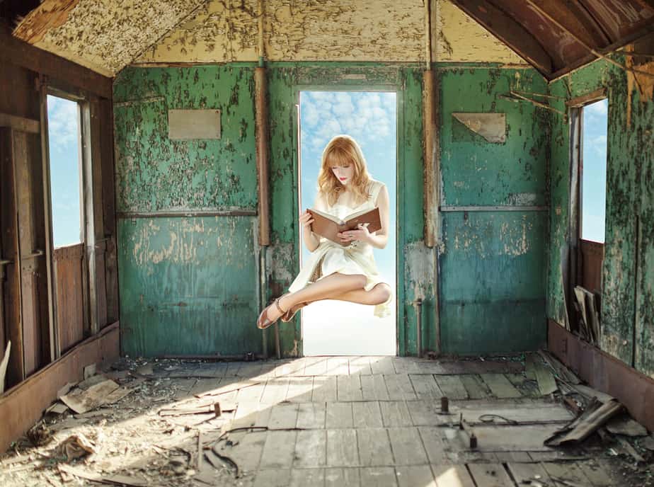 Frau liest schwebend in einem verfallenen Raum.