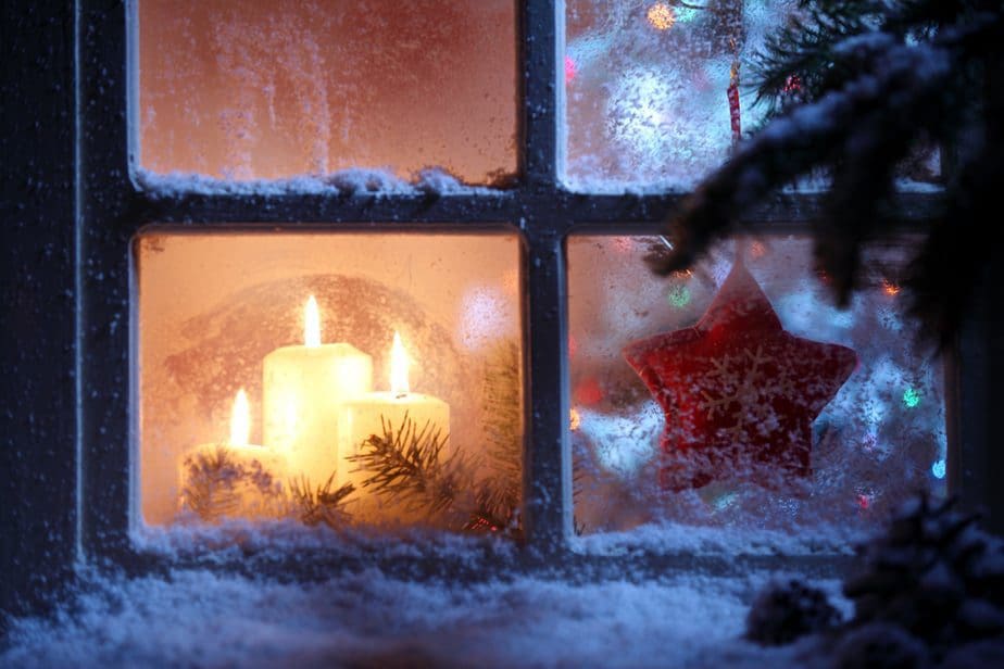 Kerzen am Fenster mit Weihnachtsdekoration