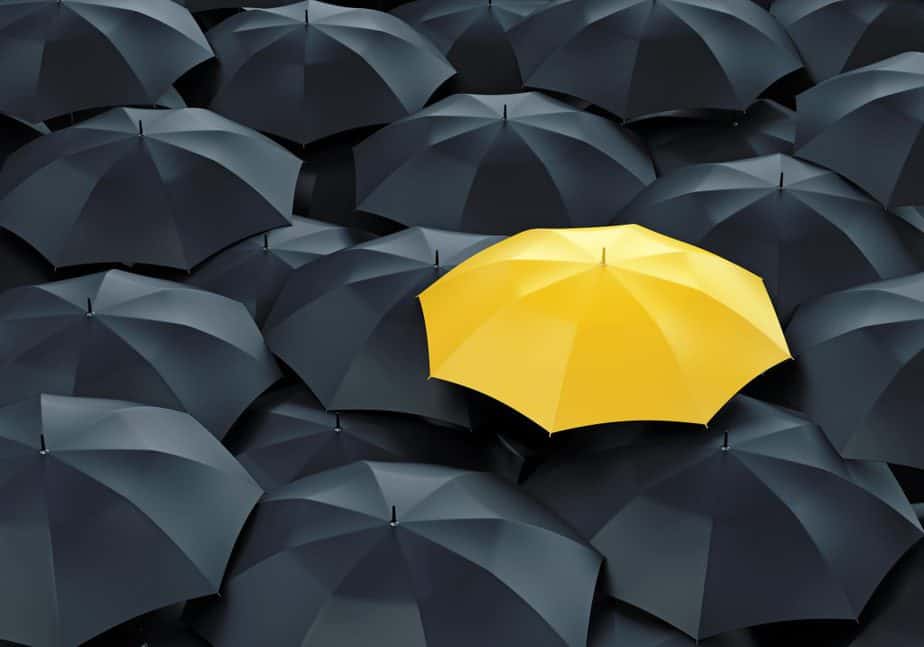 Gelber Regenschirm unter schwarzen Regenschirmen