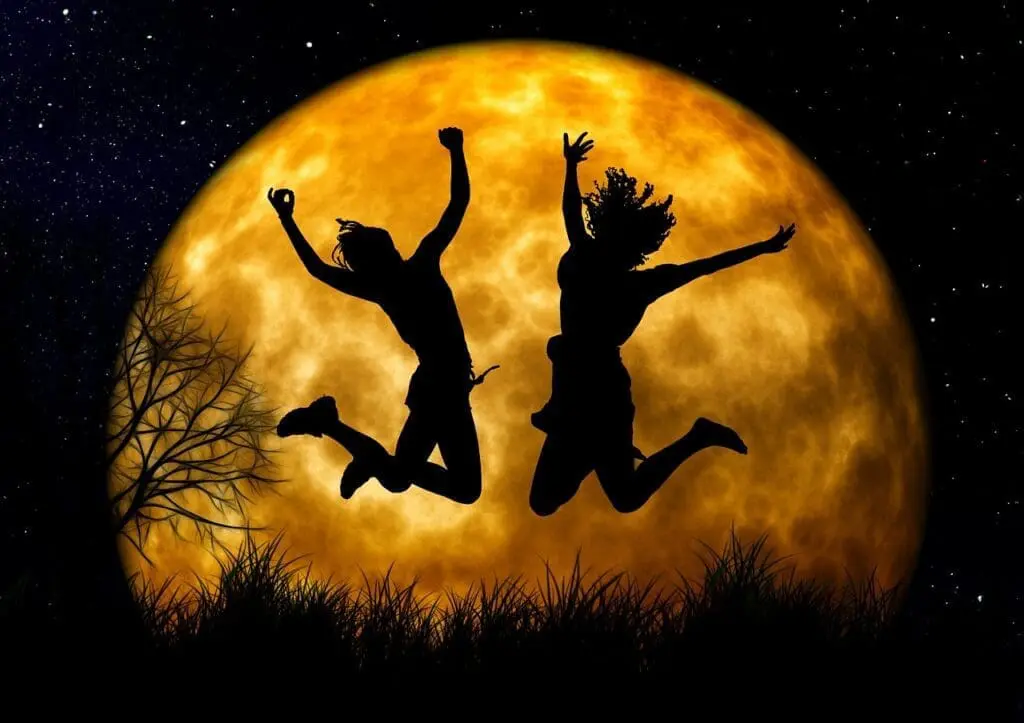 Zwei Silhouetten springen vor einem großen Vollmond