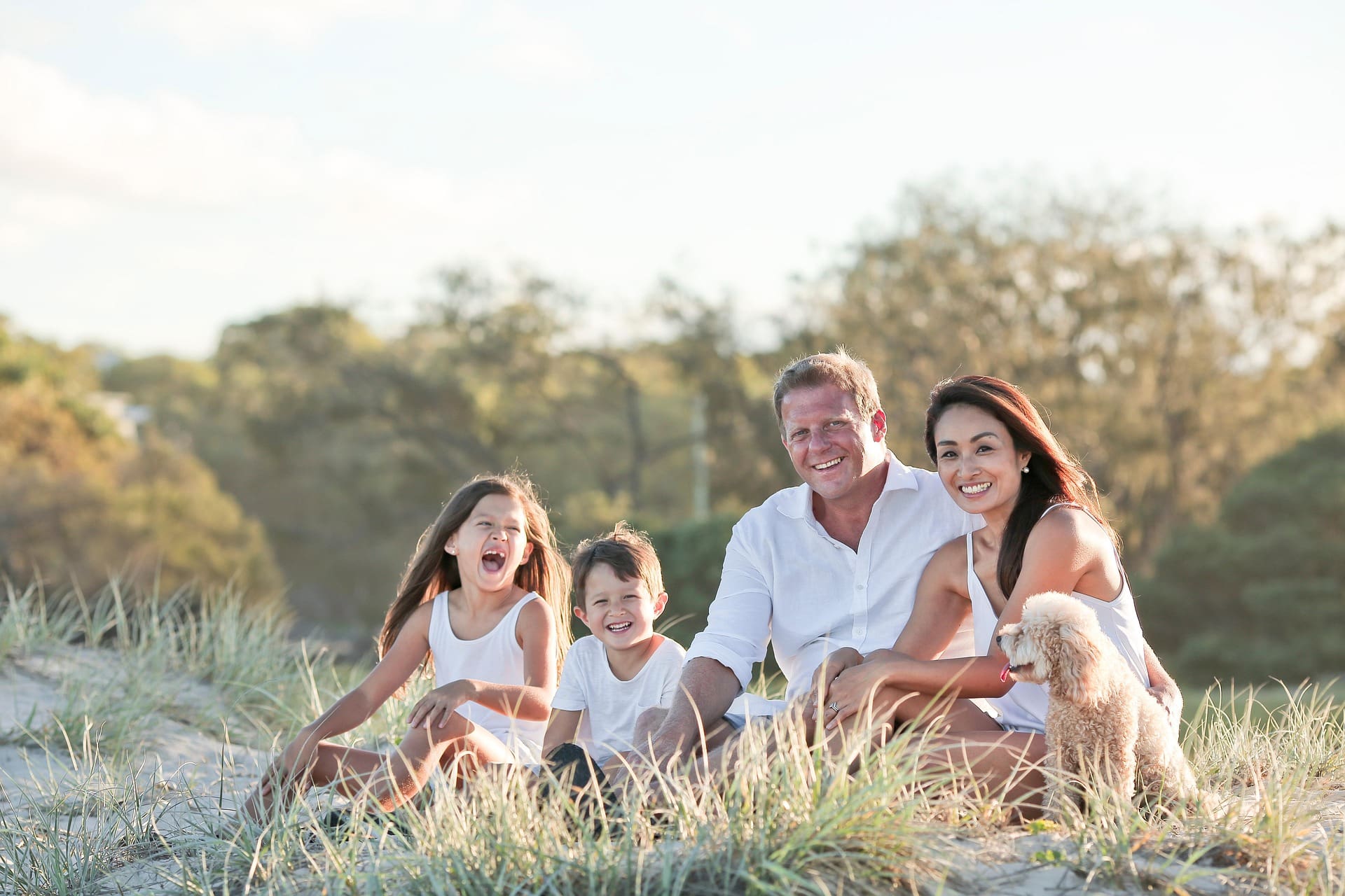 Glückliche Familie mit Hund sitzt am Strand.